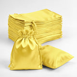 Yellow satin drawstring bags stacked and displayed on a plain background.