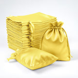 Yellow satin drawstring bags stacked and displayed in various sizes.