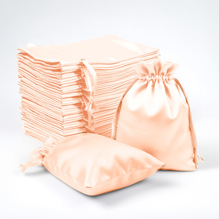 Stack of peach satin drawstring bags on a white background.