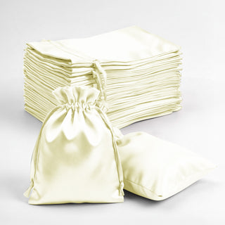 Satin drawstring bags in ivory color, stacked and one bag open.