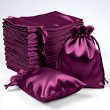 Stack of purple satin drawstring bags in various sizes on a plain background