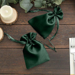 Green satin drawstring bags on a wooden table.