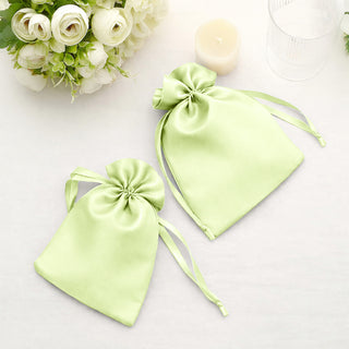 Green satin drawstring bags on a table with floral accents.