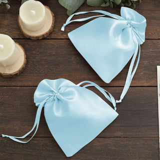 Blue satin drawstring bags on wooden surface.