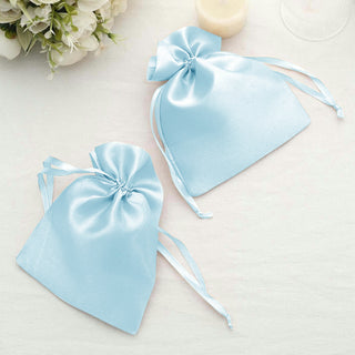 Two light blue satin drawstring bags on a soft white surface.