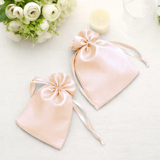 Satin drawstring bags in soft pink on a light surface with floral accents.