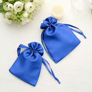 Royal blue satin drawstring bags on a light surface.