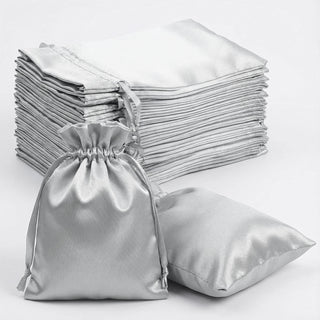 Silver satin drawstring bags stacked with one bag laid flat.