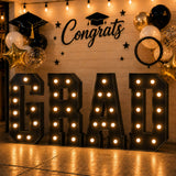 Graduation party backdrop with “GRAD” letters, balloons, and “Congrats” sign