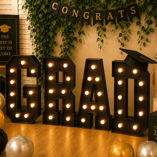 Graduation party decoration with illuminated BEHAL letters and cap banner
