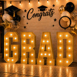 Graduation party backdrop with gold GRA letters, balloons, and Congrats sign