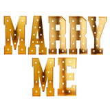 Gold marquee letters spelling “Marry Me” on white background#whtbkgd