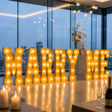 Illuminated “MARRY ME” proposal sign in modern luxury wedding venue