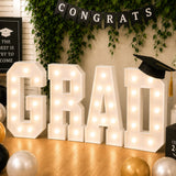 Graduation party decor with illuminated “GRAD” letters and cap banner
