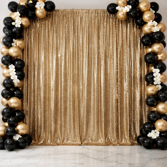 Gold sequin backdrop with black and gold balloon arch for events or photography.