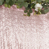 Rose gold sequin backdrop with greenery and white flowers.