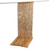 Gold sequin fabric draped on a rod against a white background#whtbkgd