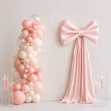 Pastel pink balloon arch with satin bow and candles for elegant party decor