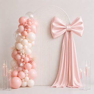 Pastel pink balloon arch with satin bow and candles for elegant party decor