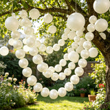 White balloon heart hanging in a sunlit garden tree