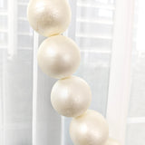 Cream-colored decorative spheres with textured surface hanging in a bright interior.
