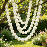 White pearl garlands hanging from tree branches in a sunny garden