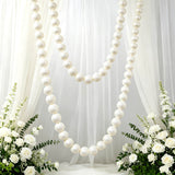 Elegant white wedding backdrop with pearl garlands and floral arrangements