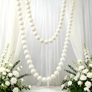 Elegant white wedding backdrop with pearl garlands and floral arrangements