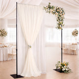 Elegant wedding arch with draped fabric and floral arrangement.