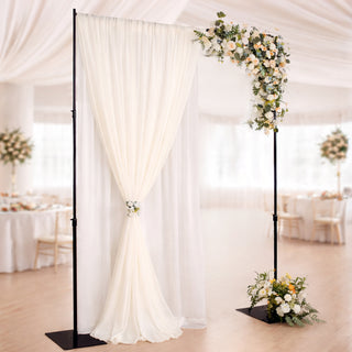 Elegant wedding arch with draped fabric and floral arrangement.