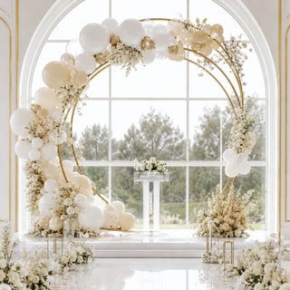 Elegant white and gold balloon arch wedding backdrop with floral arrangements