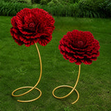 Two red floral garden sculptures with gold stands on green lawn