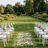 Elegant wedding ceremony setup with chairs and floral decorations in a garden.