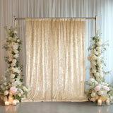 Elegant beige velvet backdrop with floral arrangements and candles for events.