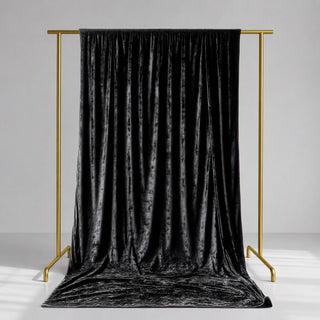 Black velvet curtain on gold clothing rack in minimalist studio setting