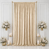 Gold wedding backdrop with champagne drape, white flowers, and candles
