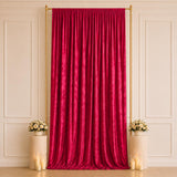 Elegant red velvet backdrop with gold frame, floral pedestals, and candles