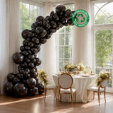 Black biodegradable balloons arranged in an arch over an elegant dining setup.