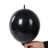 Black balloon held in hand against a plain background