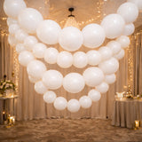 Elegant white balloon garland cascading from the ceiling at a festive event.