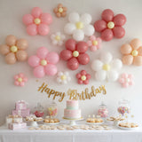 Birthday party setup with flower balloons and a decorated cake on a table.