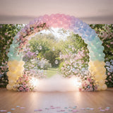 Colorful balloon arch adorned with flowers, set in a garden backdrop.