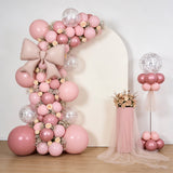 Pink balloon arch with flowers and decor for events or celebrations.