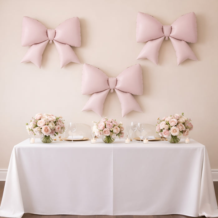 Elegant pink bows and floral centerpieces on a decorated table for an event.