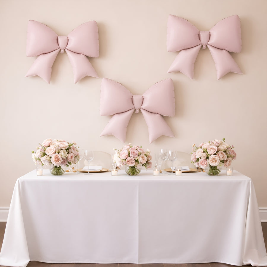 Elegant pink bows and floral centerpieces on a decorated table for an event.