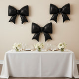 Black balloon bows above a decorated dining table with white floral centerpieces.