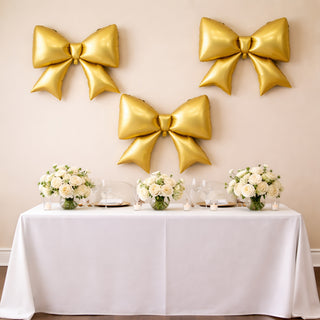 Elegant table setting with golden bows and floral centerpieces for a celebration.