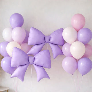 Purple and pink balloons with large decorative bows for celebrations.
