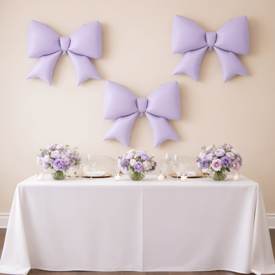 Purple balloon bows and floral centerpieces on a decorated table for an event.