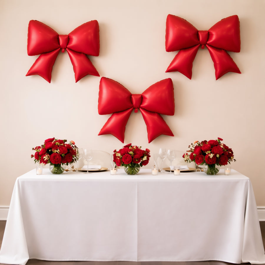 Red balloon bows and floral centerpieces on a table for festive decor.